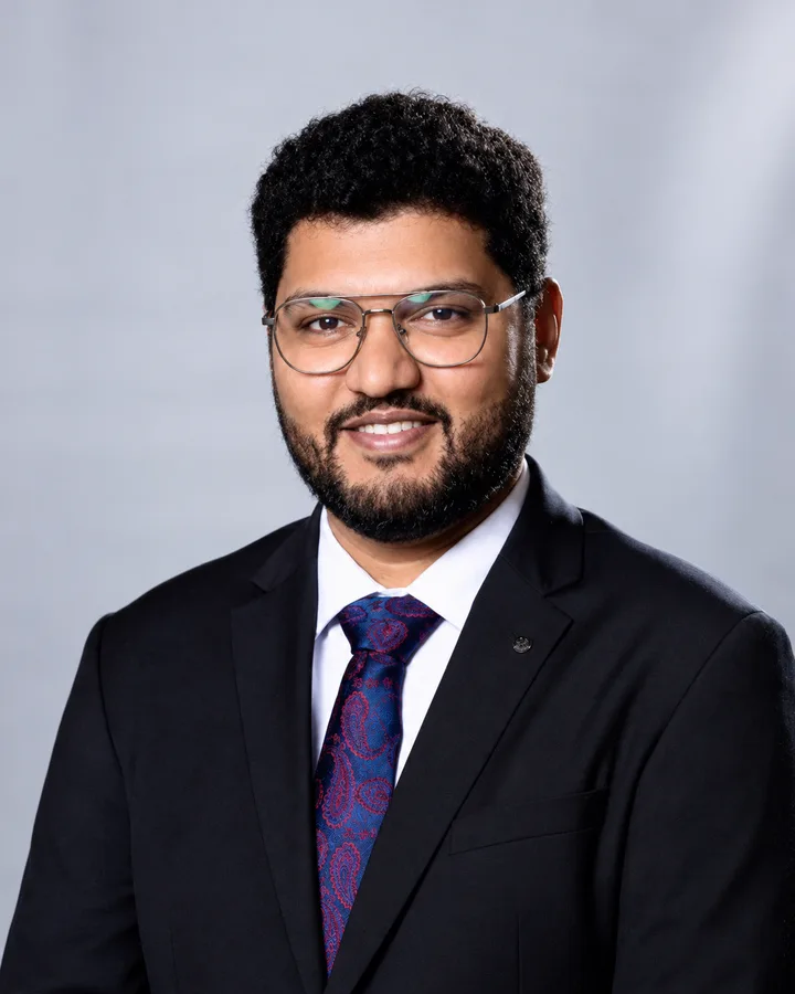 R. Veera Manoharan, in a dark suit and glasses, smiling